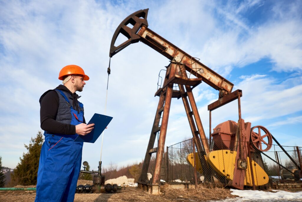 Oil man checking work of oil well pump jack.